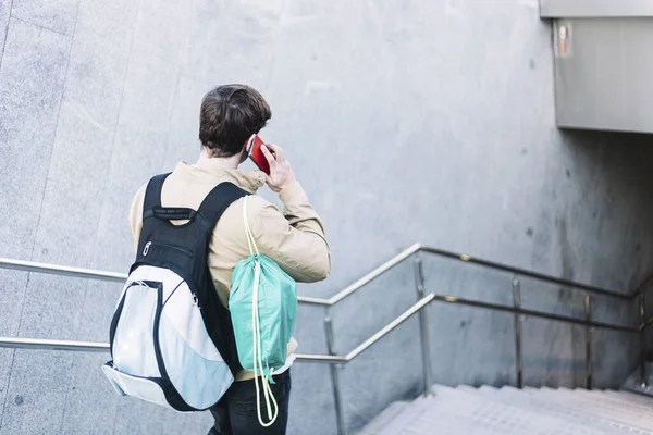 Mladý Muž Kráčí Dolů Schodech Batohem Při Použití Mobilní Venku — Stock fotografie