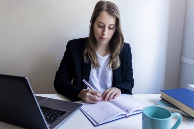 Genç girişimci kadın evde çalışıyor, iş yazıları yazıyor.