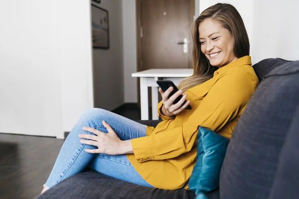 Hermosa Mujer Adulta Sentada Sofá Mientras Usa Teléfono Inteligente — Foto de Stock