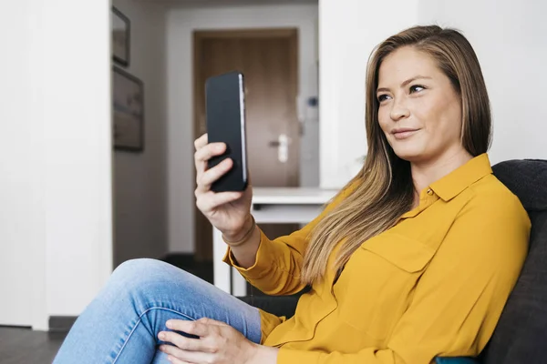 Akıllı Telefon Kullanırken Koltukta Oturan Güzel Yetişkin Kadın — Stok fotoğraf