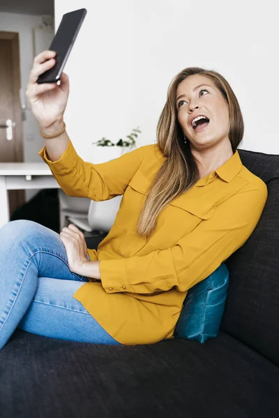 Schöne Erwachsene Frau Sitzt Auf Dem Sofa Während Sie Das — Stockfoto