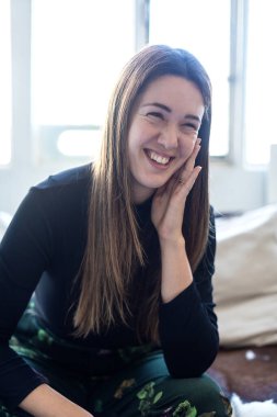 Kafasından vurulan çekici beyaz kadın kanepede oturuyor oturma odasında kanepe, gülümseyen genç kadın, kameraya bak.