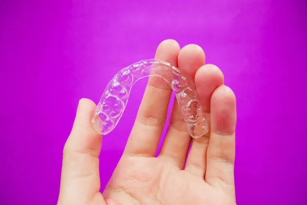 Trzymając Ręce Przezroczystymi Plastikowymi Zębami Które Izolowane Fioletowym Tle Sprzęt — Zdjęcie stockowe