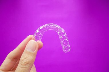 Mor arka planda izole edilmiş temiz plastik diş tutucu. Ortodontist için bir ekipman. Hastayı diş sağlığı kliniğinde ya da hastanede ortodontik cerraha verin.