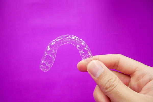 Mão Segurando Dentes Plástico Transparente Retentor Que Isolado Fundo Roxo — Fotografia de Stock