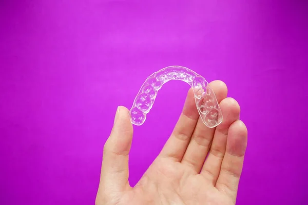 Mão Segurando Dentes Plástico Transparente Retentor Que Isolado Fundo Roxo — Fotografia de Stock