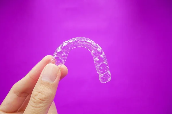 Mão Segurando Dentes Plástico Transparente Retentor Que Isolado Fundo Roxo — Fotografia de Stock