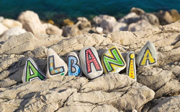 Albánie jméno z barevné malované kameny, moře pozadí — Stock fotografie