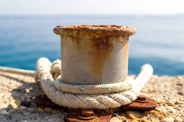 Rezavý kotvení patník, bílé lano na pozadí modré moře — Stock fotografie