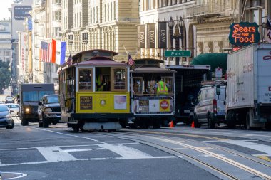 Yoğun bir San Francisco caddesinde iki kablo araba birbirinin yanından geçiyor.
