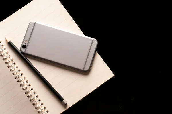 Smartphone mobiltelefon och penna på anteckningsboken använda i business office svart bakgrund — Stockfoto