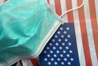 Birleşik Devletler bayrağının arka planındaki cerrahi maskesine odaklan. Sağlık maskesi. Covid-19, Pollutant PM2.5 ve başka bir virüsü önlemek için kullanılır. ABD 'yi kurtar Covid19 Sağlık Hizmetleri Konseptinden