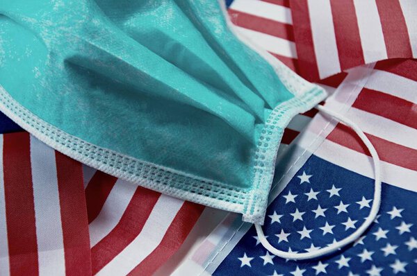Сосредоточьтесь на некоторых точках хирургической маски на фоне флага США. Маска здоровья. Используется для предотвращения ковида-19, загрязнителя PM2.5 и другого вируса. Спаси США. от Covid19 Здравоохранение
