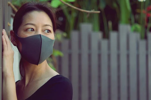 Asyalı kadın portresi, Covid-19 durumları için endişelenmesi dışında, Koyu yeşil arka planda hava kirliliğinden veya virüs salgınından korunmak için istiridye ve yüz maskesi takıyor.