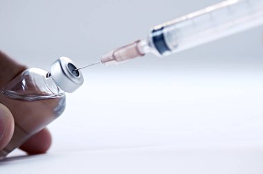 Bir doktorun elinde cam bir ilaç şişesi. Aşısı olan bir şişe hastanede el ele tutuşur. Teknisyen aşıyı hazırlar. Aşılama yoluyla virüslerin yayılmasını önlemek.