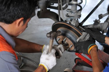 Otomobil tamircisi yeni lastik değiştirme sürecinde, garajda araba freni tamiri, tekerleği sökülmüş bir arabanın frenleri, garajda araba freni parçası, tekerlekleri olmayan bir araba fren diski. 