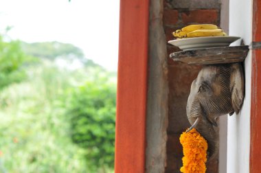 Ganesha tapınağı, Hindu tanrısı Ganesha 'nın küçük ölçekli putu, sarı çiçekli ahşap, insanlar ona şans dilemek için dua ediyor.