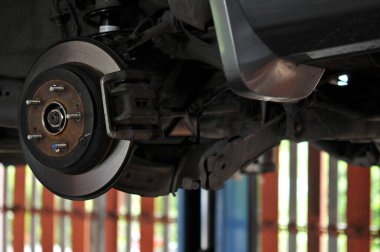 Otomobil tamircisi yeni lastik değiştirme sürecinde, garajda araba freni tamiri, tekerleği sökülmüş bir arabanın frenleri, garajda araba freni parçası, tekerlekleri olmayan bir araba fren diski. 