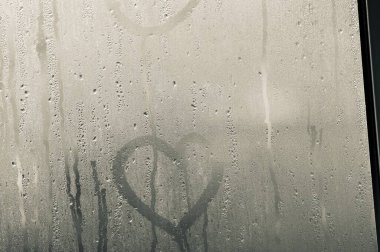 Şeffaf cam ve bir damla su var ve dışarıdaki camın arkasını görebiliyor ama net değil. Yağmur yağdığında aynada buhar ya da buhar