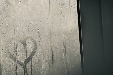 Şeffaf cam ve bir damla su var ve dışarıdaki camın arkasını görebiliyor ama net değil. Yağmur yağdığında aynada buhar ya da buhar