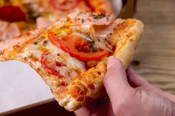 Lezzetli bir dilim pizza bir kutu alarak el.