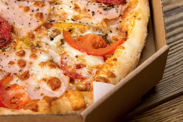 Pizza caliente y sabrosa lista para comer en una caja de cartón . — Foto de Stock