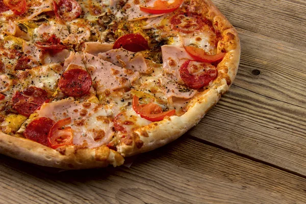 Pizza caliente y sabrosa lista para comer sobre un fondo de madera . — Foto de Stock