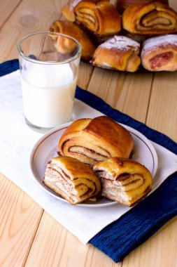 Tarçınlı çörek ve bir bardak süt ahşap arka plan üzerinde.