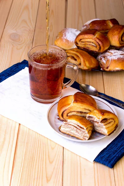 Zimtbrötchen und eine Tasse schwarzen Tee auf einem hölzernen Hintergrund. — Stockfoto