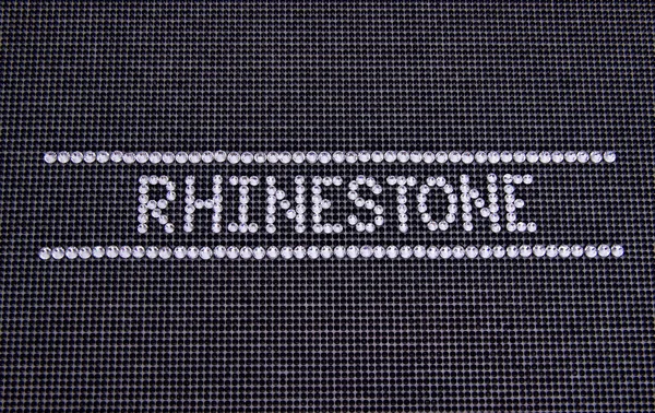 Kata RHINESTONE dibuat rhinestones pada latar belakang kanvas hitam — Stok Foto