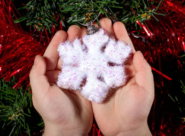 Juguete de Navidad blanco copo de nieve niño sosteniendo las manos. Tarjeta postal . — Foto de Stock