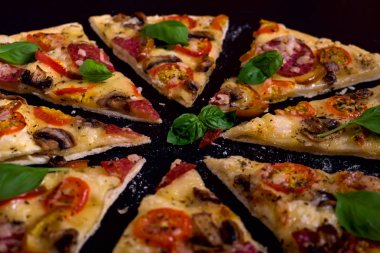 Sıcak ve lezzetli pizza salam domates peynir ve siyah bir ahşap arka plan üzerinde yemeye hazır mantar ile.