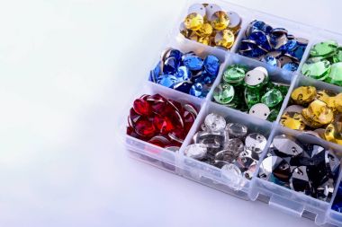 Parlak renkli rhinestones beyaz zemin üzerinde bir kutu şeklinde yuvarlak.