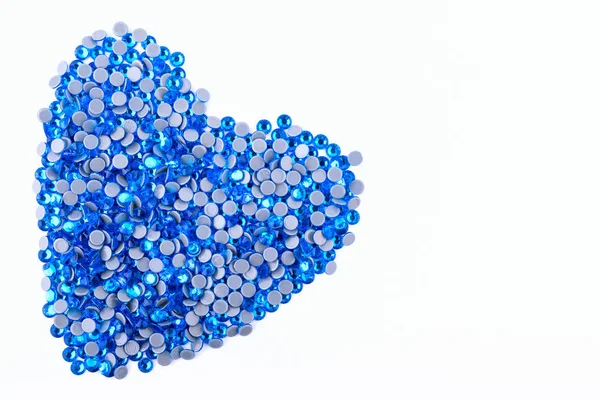 A lot of blue rhinestones made in the shape of a heart on a white background. Top view. — Stock Photo, Image