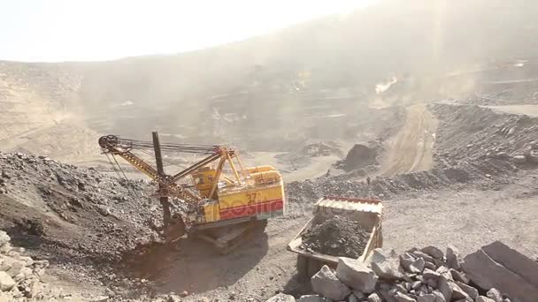 Excavatrice et benne à ordures dans la carrière, pelle charge les matières premières dans la benne à ordures, travail dans la carrière de minerai de fer, panorama . — Video