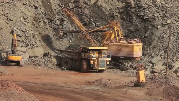 Excavadora y volquete en la cantera, la excavadora carga las materias primas en el volquete, el trabajo en la cantera de mineral de hierro . — Vídeos de Stock