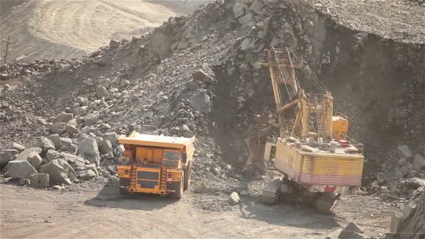 Excavadora y volquete en la cantera, la excavadora carga las materias primas en el volquete, el trabajo en la cantera de mineral de hierro . — Vídeo de stock