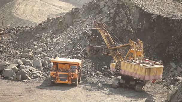 Excavadora y volquete en la cantera, la excavadora carga las materias primas en el volquete, el trabajo en la cantera de mineral de hierro . — Vídeos de Stock