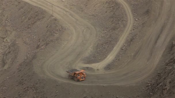 Um grande basculante cava através de uma carreira, um caminhão industrial dragas carga em sua pedreira, um grande dumper amarelo — Vídeo de Stock