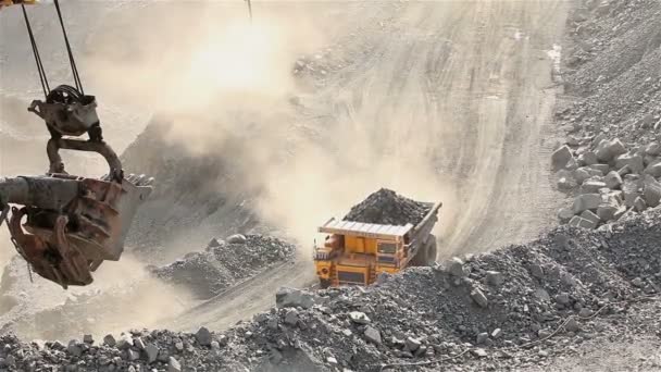 Een grote Kipper graaft door een carrière, een industriële vrachtwagen baggert lading in de steengroeve, een grote gele dumper — Stockvideo