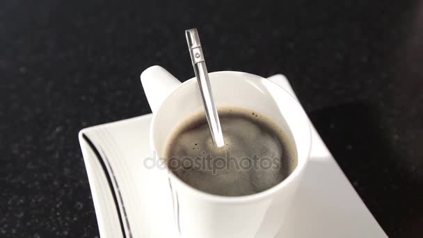 Μια γυναίκα ανακατεύει τον καφέ με ένα κουτάλι, ένα κορίτσι ανακατώνει ζάχαρης σε ένα κουτάλι του καφέ, γκρο πλαν — Αρχείο Βίντεο