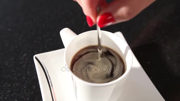 Una mujer revuelve un café con una cuchara, una chica revuelve azúcar en una cuchara de café, de cerca — Vídeo de stock