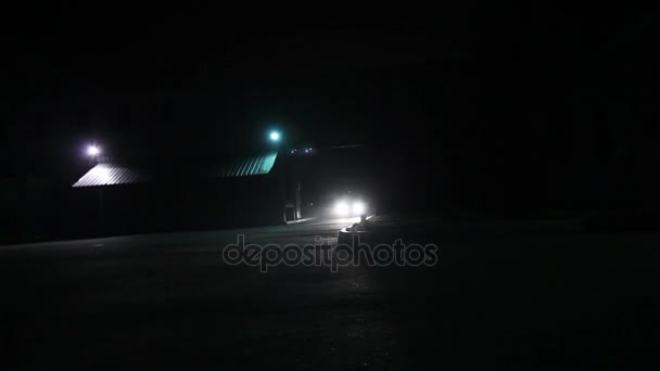 El coche viaja al edificio por la noche, las luces brillan, las llamadas de coche en el patio, los faros de coche por la noche, los faros de coche — Vídeos de Stock