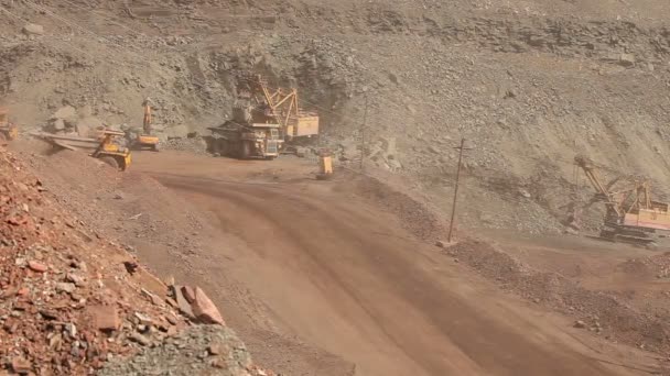 A large tipper digs through a career, an industrial truck dredges cargo in its quarry, a large yellow dumper — Stock Video