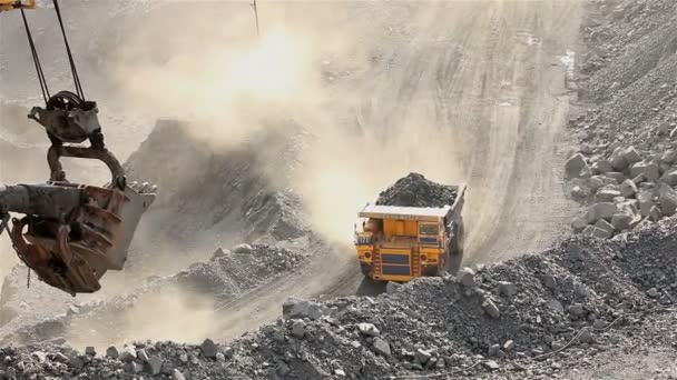 Een grote Kipper graaft door een carrière, een industriële vrachtwagen baggert lading in de steengroeve, een grote gele dumper — Stockvideo