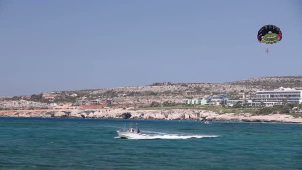 El barco enrolla a un hombre en un paracaídas, entretenimiento en el mar, hermosa costa, buen tiempo — Vídeos de Stock