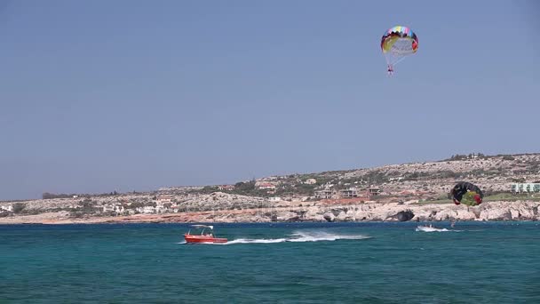 O barco rola um homem em um paraquedas, entretenimento marítimo, bela costa, bom tempo — Vídeo de Stock