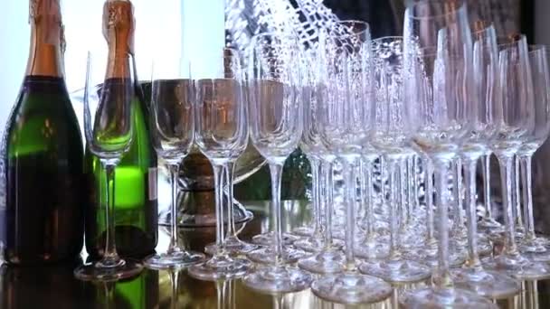 Bicchieri sul tavolo da buffet, una bottiglia di champagne, design del ristorante, interni, interni, movimento regolare della fotocamera lungo il tavolo, file di bicchieri di vino sul tavolo, profondità di campo poco profonda — Video Stock