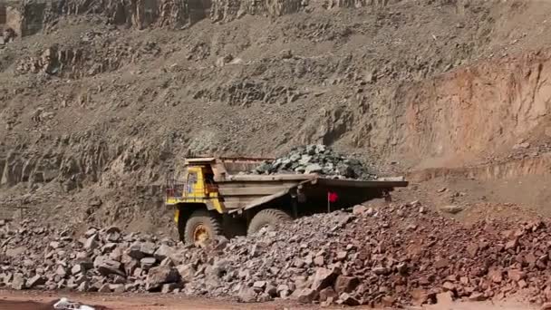Een grote Kipper graaft door een carrière, een industriële vrachtwagen baggert lading in de steengroeve, een grote gele dumper — Stockvideo