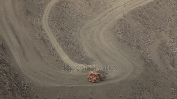 Un volquete grande cava a través de una carrera, un camión industrial draga carga en su cantera — Vídeo de stock